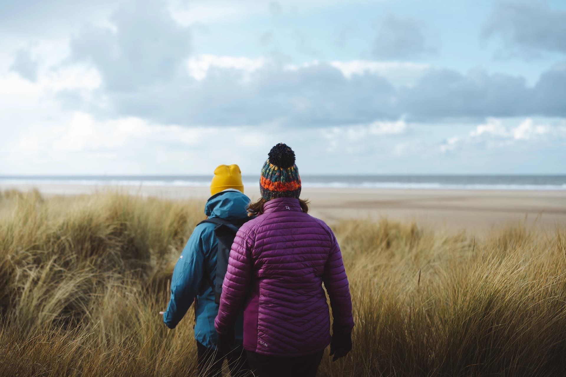 People walking through coastal grasslands toward the beach at Holkham, a National Landscape